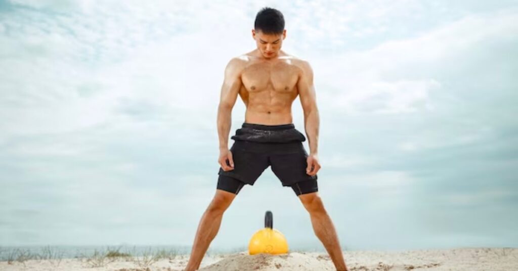 a man on the sand doing exercise with kettlebelll