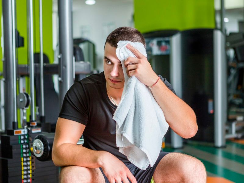 a man wiping off his sweat in gym