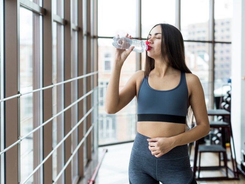 a women drinking water after a workout session 