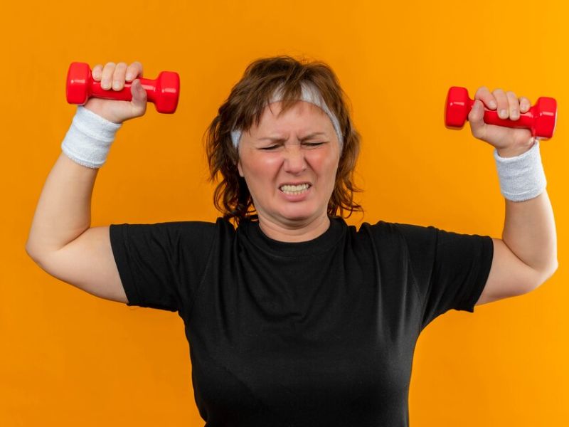 a women struggling to pick up weights