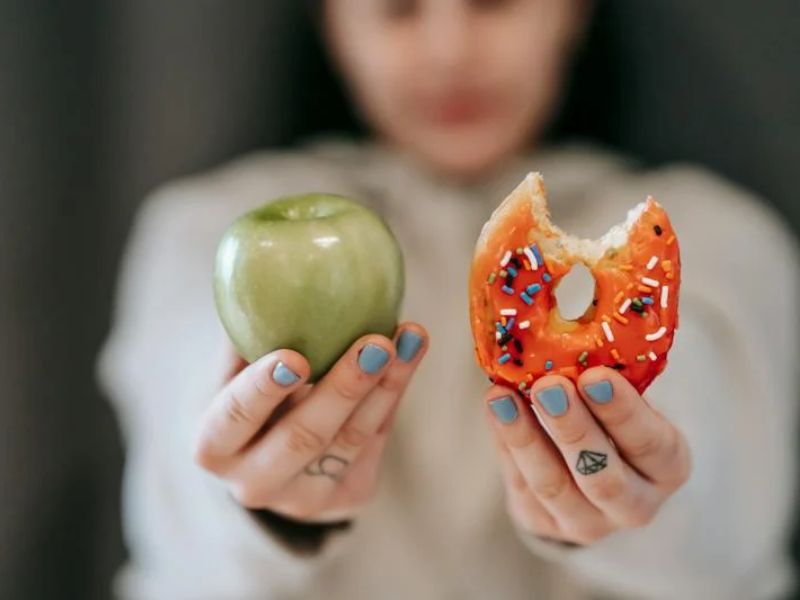 a lady showing apple and a donut 