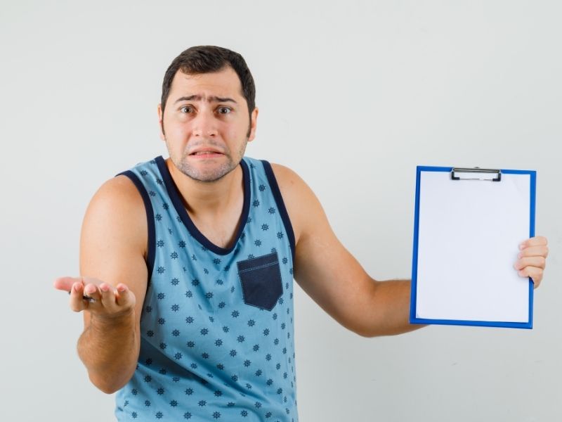 A person holding a weight chart with a confused expression.
