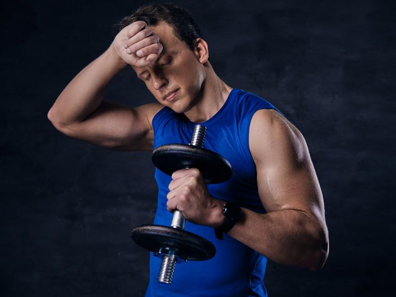 a person with confused expression with dumbbell in his hand